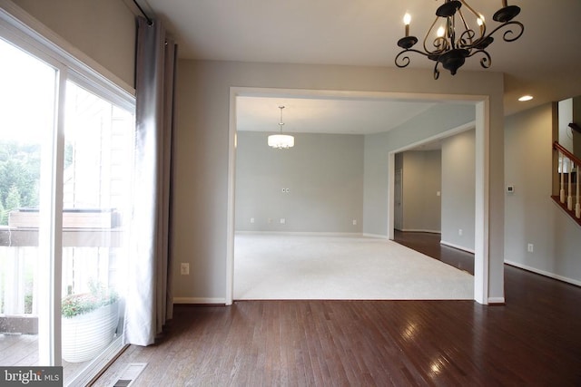  - empty room with a chandelier, plenty of natural light, and wood finished floors