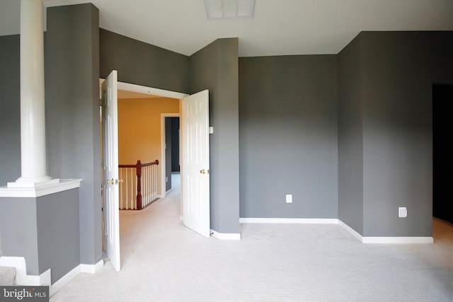  - empty room featuring decorative columns and light carpet