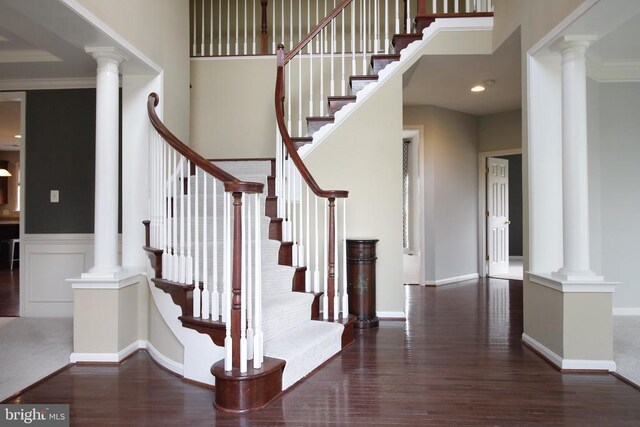 - stairway featuring wood finished floors and decorative columns