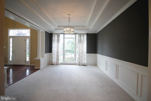  - foyer entrance with ornate columns, a chandelier, a decorative wall, healthy amount of natural light, and a tray ceiling