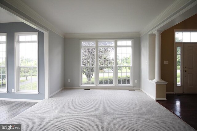  - foyer featuring decorative columns, healthy amount of natural light, crown molding, and wood finished floors