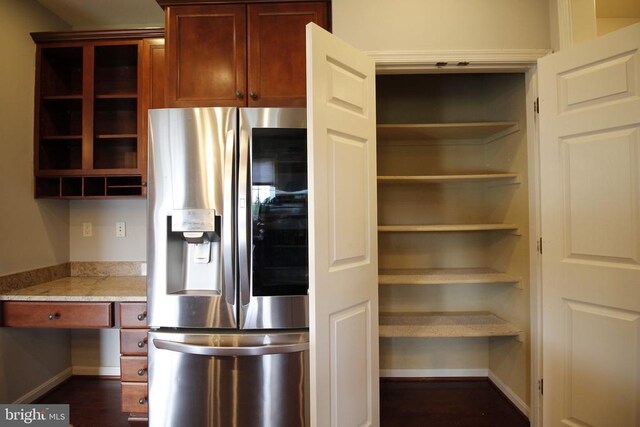  - kitchen featuring stainless steel refrigerator with ice dispenser, open shelves, dark wood-type flooring, and light stone countertops