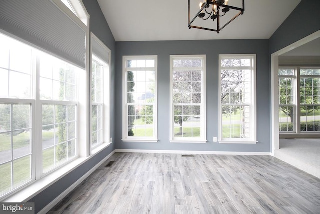  - unfurnished sunroom with vaulted ceiling, a chandelier, healthy amount of natural light, and wood finished floors