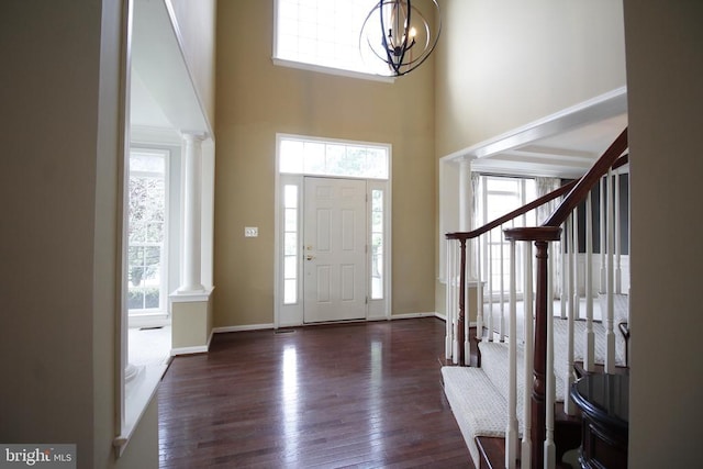  - entrance foyer with ornate columns, a towering ceiling, wood finished floors, a chandelier, and stairway