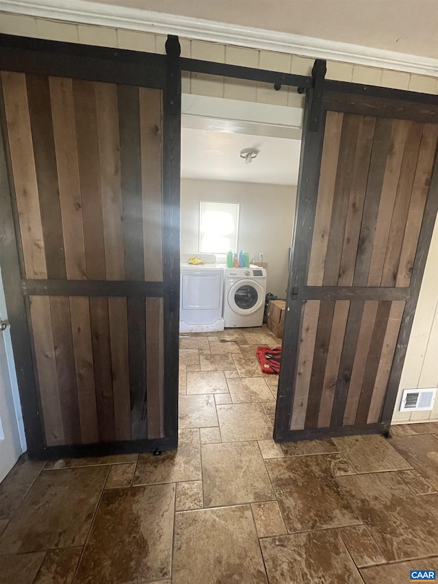 3133 Burnley Station Rd, Barboursville, VA 22923 - clothes washing area with a barn door, stone tile flooring, and washing machine and dryer