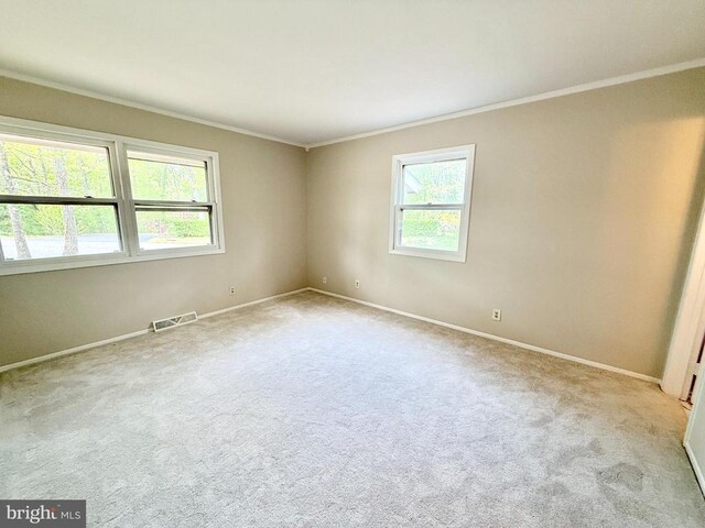 carpeted empty room featuring crown molding and baseboards