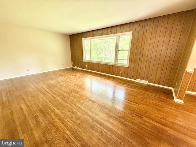 spare room with wood finished floors, baseboards, and wooden walls