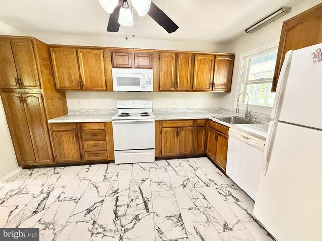 kitchen featuring white appliances, a sink, light marble finish flooring, and brown cabinetry