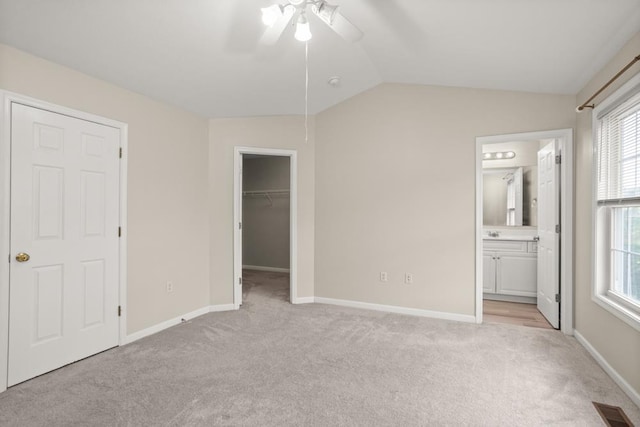 2890 Crystal Spring Ln, Rockingham, VA 22801 - unfurnished bedroom featuring light colored carpet, multiple windows, a walk in closet, vaulted ceiling, and baseboards