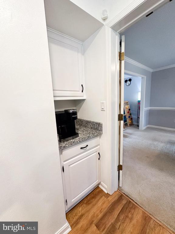 bar area with crown molding, light wood-style floors, and baseboards