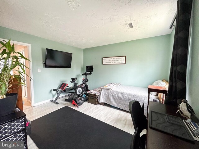 bedroom with wood finished floors, a textured ceiling, and baseboards