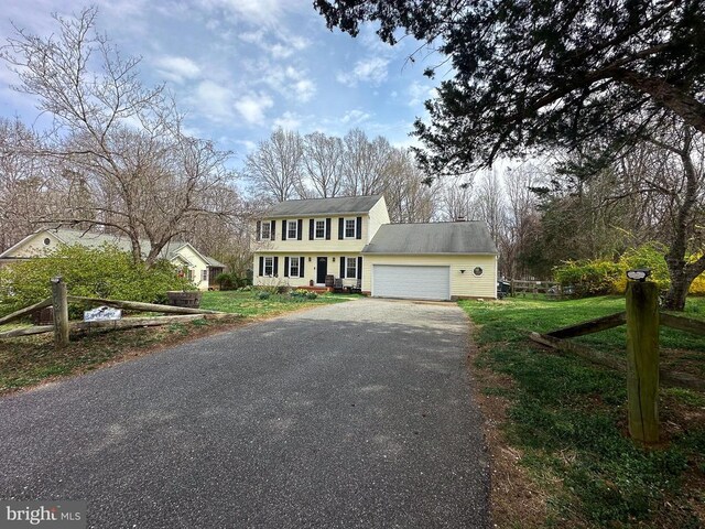 colonial inspired home with asphalt driveway and a garage
