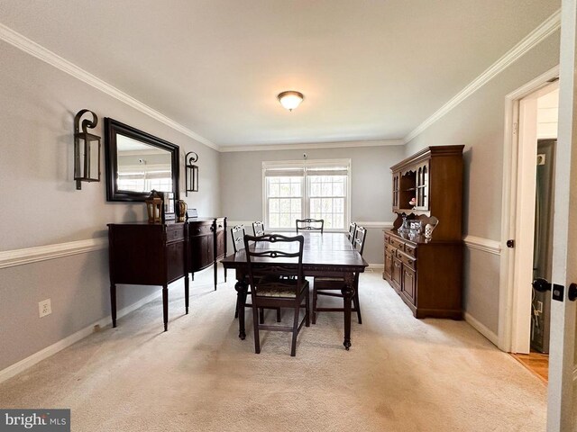 dining space with ornamental molding, light carpet, and baseboards