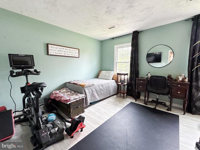 bedroom featuring a textured ceiling and wood finished floors