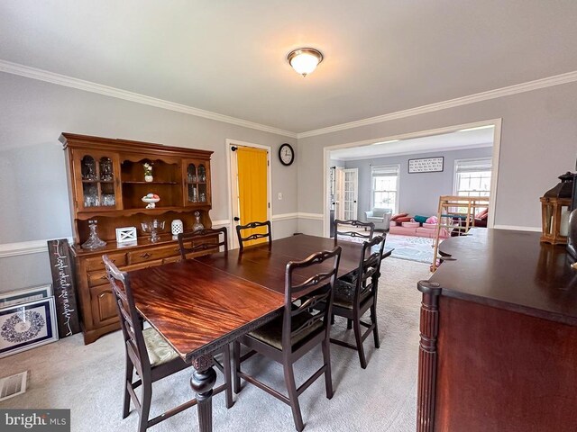 dining room with ornamental molding and light colored carpet