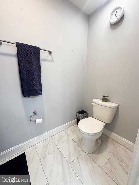 bathroom with marble finish flooring, toilet, and baseboards