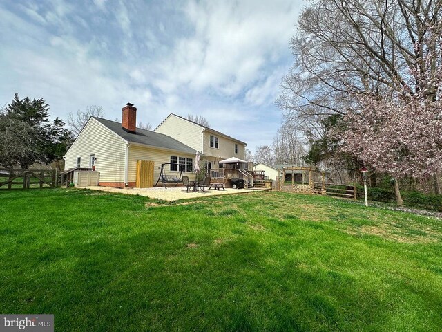 back of house with a chimney and a wooden deck
