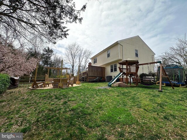 rear view of house with a playground, a trampoline, central air condition unit, and a deck