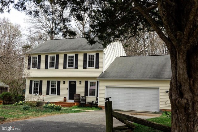 colonial inspired home with asphalt driveway and an attached garage