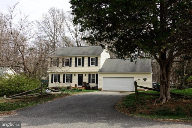 colonial-style house featuring asphalt driveway and an attached garage