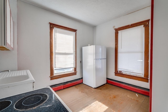 182 Church St, Broadway, VA 22815 - kitchen with freestanding refrigerator, a textured ceiling, light wood-style flooring, and a baseboard radiator