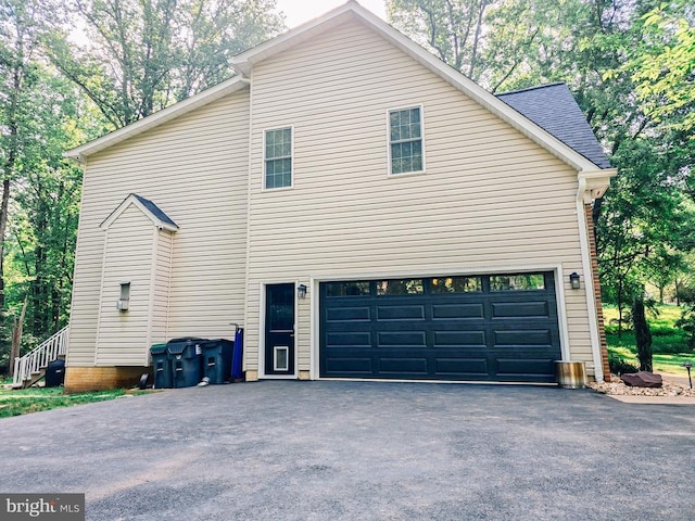  - view of side of home featuring asphalt driveway and an attached garage