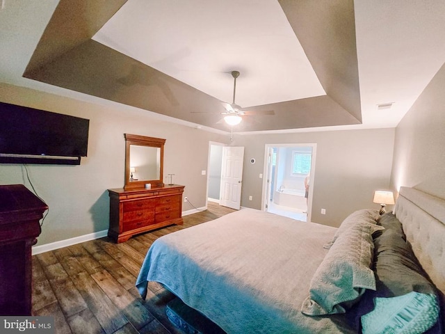  - bedroom with a tray ceiling, wood finished floors, ensuite bathroom, and a ceiling fan