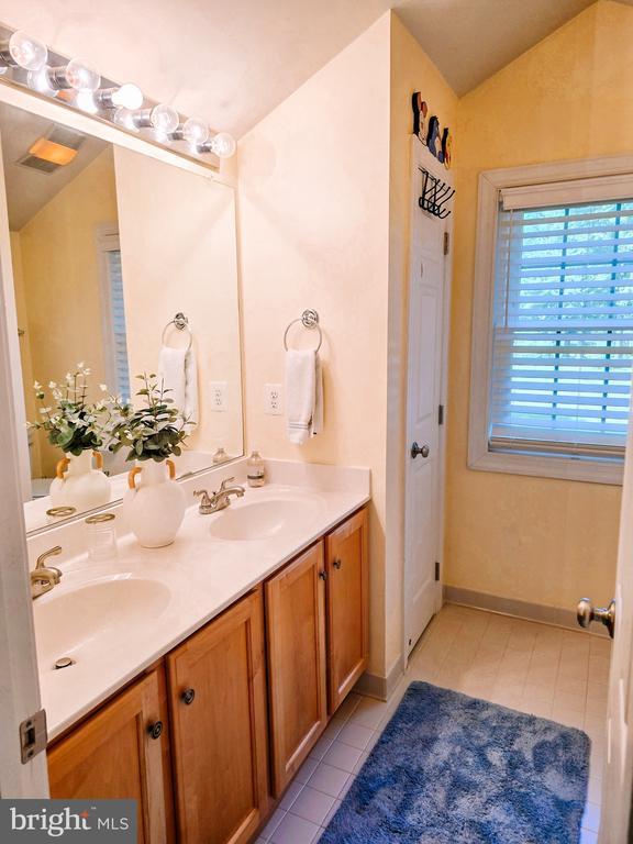  - full bath featuring double vanity, tile patterned floors, and lofted ceiling