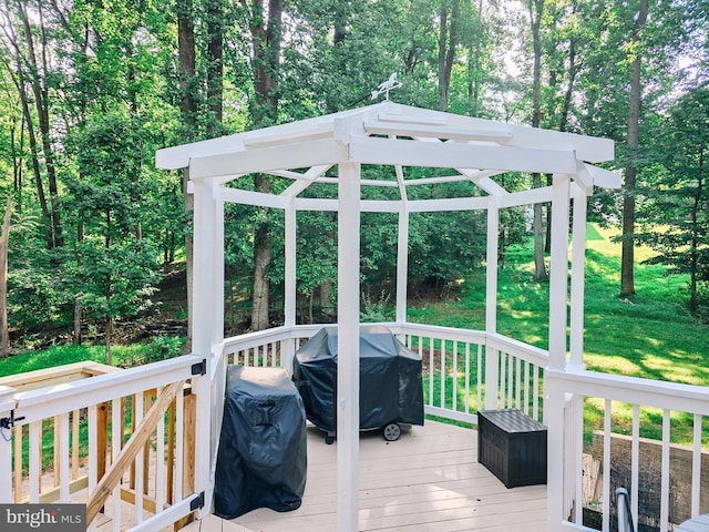  - wooden deck featuring area for grilling, view of wooded area, and a yard