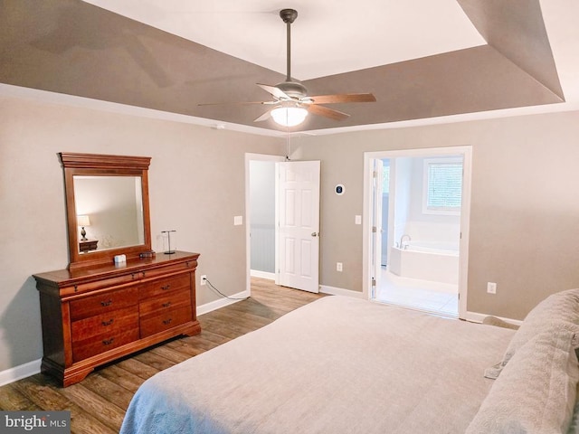  - bedroom with wood finished floors, a raised ceiling, and ensuite bath
