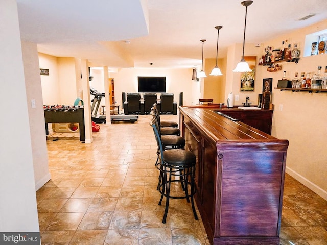  - indoor wet bar featuring baseboards and decorative light fixtures