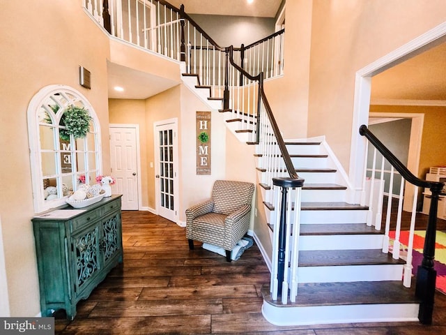  - staircase featuring a towering ceiling and wood finished floors