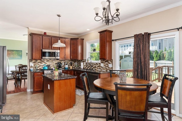 5930 Copper Mountain Dr W, Spotsylvania, VA 22553 - kitchen featuring appliances with stainless steel finishes, a center island, a sink, ornamental molding, and tasteful backsplash