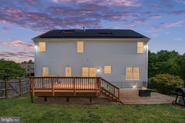 5930 Copper Mountain Dr W, Spotsylvania, VA 22553 - back of property at dusk with an outdoor fire pit, a deck, and roof mounted solar panels