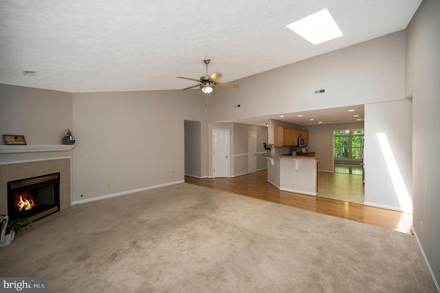 317 Edgehill Dr, Locust Grove, VA 22508 - unfurnished living room featuring light carpet, a tile fireplace, ceiling fan, baseboards, and high vaulted ceiling