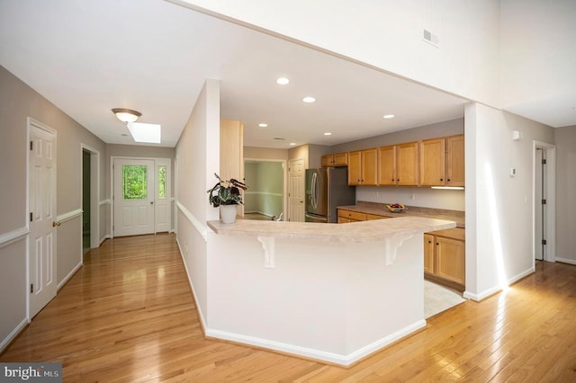 317 Edgehill Dr, Locust Grove, VA 22508 - kitchen with stainless steel fridge, light wood finished floors, a breakfast bar area, a peninsula, and recessed lighting