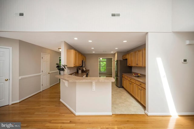 317 Edgehill Dr, Locust Grove, VA 22508 - kitchen featuring appliances with stainless steel finishes, a peninsula, a breakfast bar area, light wood-style flooring, and recessed lighting