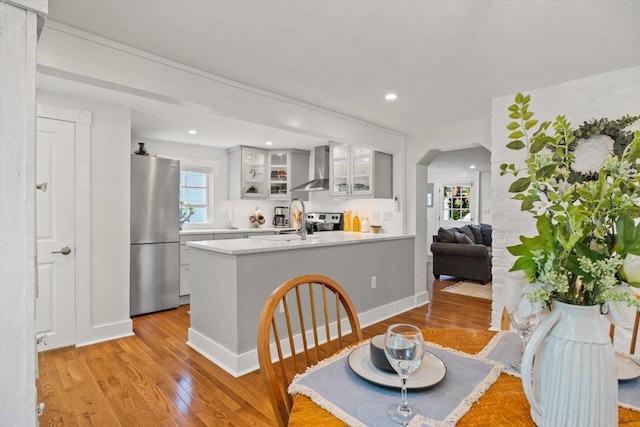 dining space with arched walkways, light wood-style floors, and recessed lighting