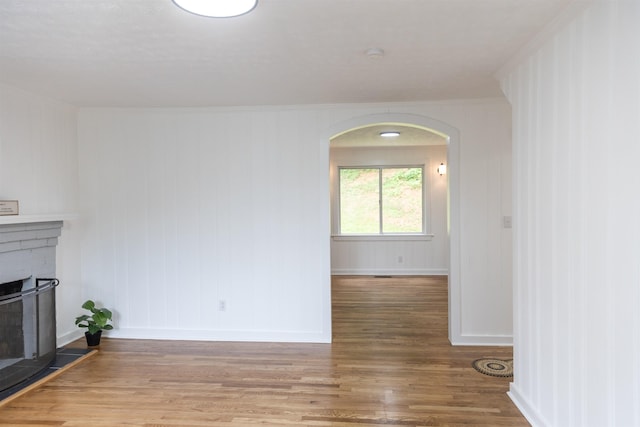 164 28th St E, Buena Vista, VA 24416 - unfurnished living room featuring wood finished floors, arched walkways, ornamental molding, and a fireplace