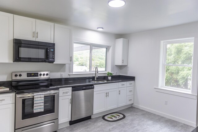 164 28th St E, Buena Vista, VA 24416 - kitchen with stainless steel appliances, plenty of natural light, dark countertops, and white cabinetry