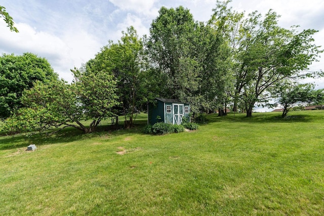 view of green lawn with a storage unit and an outdoor structure