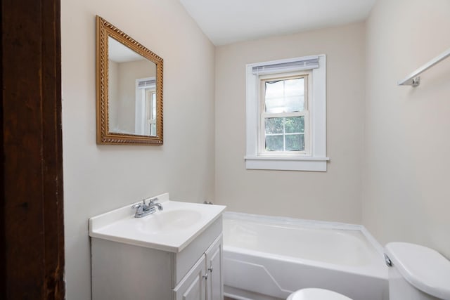 bathroom with toilet, a bath, and vanity