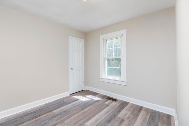 empty room with wood finished floors, baseboards, and plenty of natural light