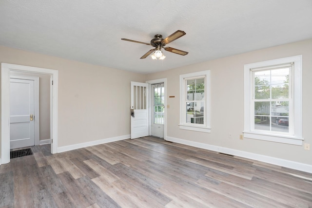 spare room with ceiling fan, wood finished floors, baseboards, and a textured ceiling