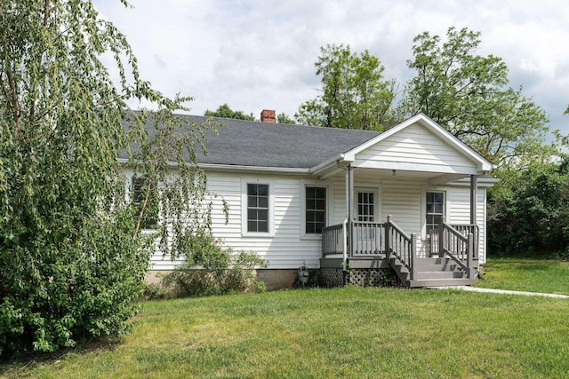 view of front of property featuring a chimney, a front yard, covered porch, and roof with shingles