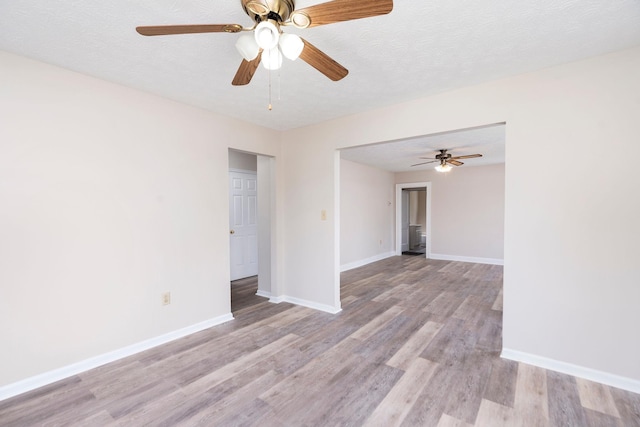 empty room featuring light wood-type flooring, baseboards, a ceiling fan, and a textured ceiling
