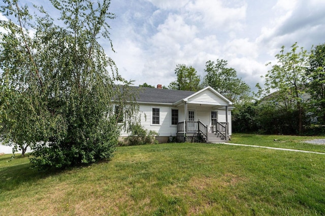 view of front of home featuring covered porch, a front lawn, and a chimney