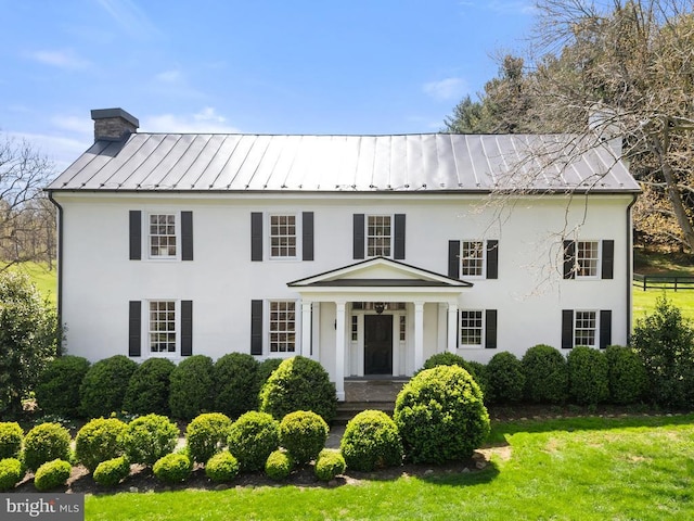  - view of front of home with metal roof, stucco siding, a standing seam roof, and a chimney
