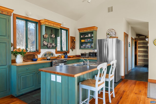 7122 Harris Mountain Ln, Dyke, VA 22935 - kitchen featuring stainless steel appliances, vaulted ceiling, wood finished floors, a center island with sink, and open shelves