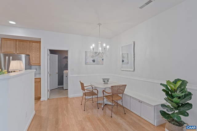 dining room with a wainscoted wall, washer / dryer, visible vents, a notable chandelier, and light wood-style floors